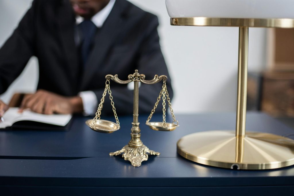 Elegantes Anwaltsbüro mit Nahaufnahme einer goldenen Justitia-Waage auf einem eleganten dunklen Schreibtisch.