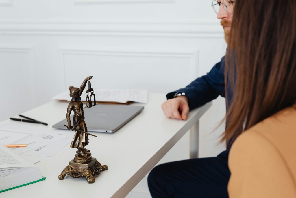 Professionelle Atmosphäre mit Anwälten und einer Justitia-Statue, die über juristische Dokumente diskutieren.